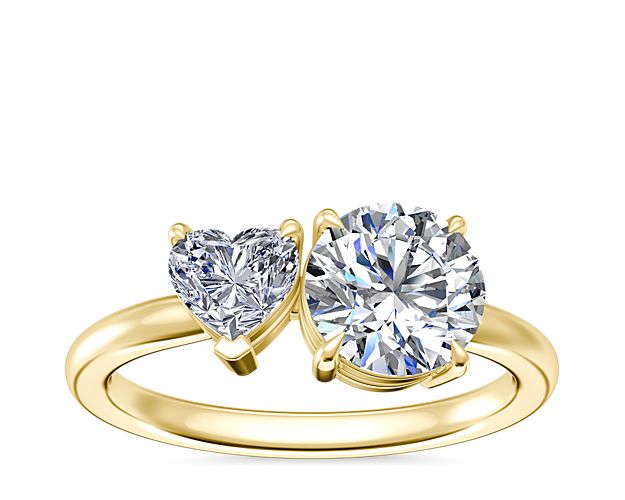 Made of lustrous 18k yellow gold, this engagement ring features an eye-catching two-stone design. A heart-shaped diamond and round, princess or pear-cut diamond give it dramatic sparkle.