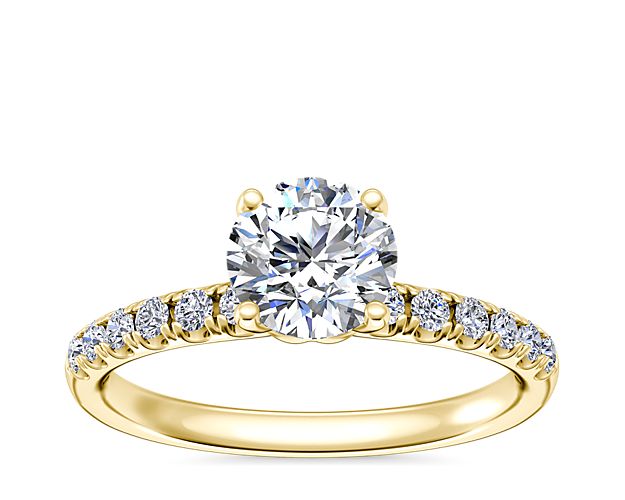 Take the breath away with this stunning engagement ring featuring a beautiful center stone complemented by shimmering micropavé diamonds sparkling along the shank. The warm luster of the 14k yellow gold design highlights the stones.