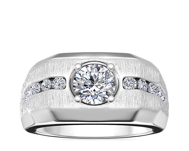 A brushed finish adds a luxurious contemporary look to this sophisticated engagement ring crafted from 18k white gold. The center setting supports a round, cushion, princess (prince), emerald-cut, radiant, or oval diamond, and is accented by delicate channel-set diamonds.