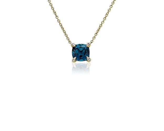 The moody deep blue hue of the cushion-cut London blue topaz set in this pendant makes it a stunning piece. 14k yellow gold design beautifully complements the main stone with a warm luster. Shimmering accent diamonds lend sparkle to the prongs holding the topaz in place.