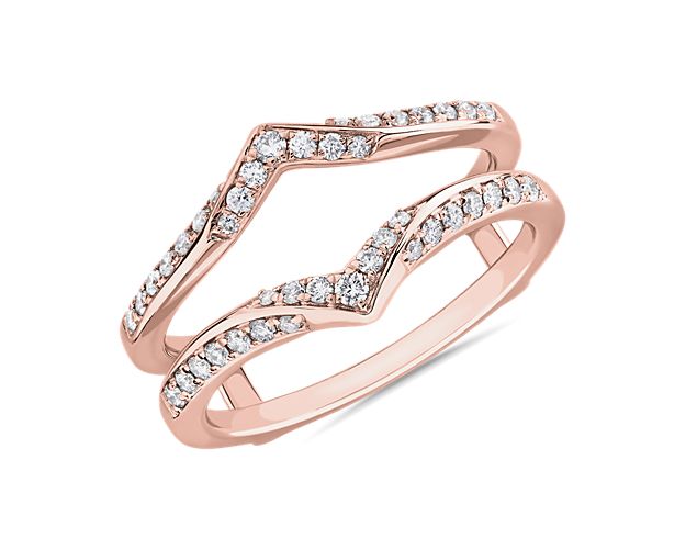This diamond guard features a split shape that lets an engagement ring nestle beautifully at its centre. The 14k rose gold design features graceful points and is set with shimmering diamonds to make it a luxurious complement to your ring.