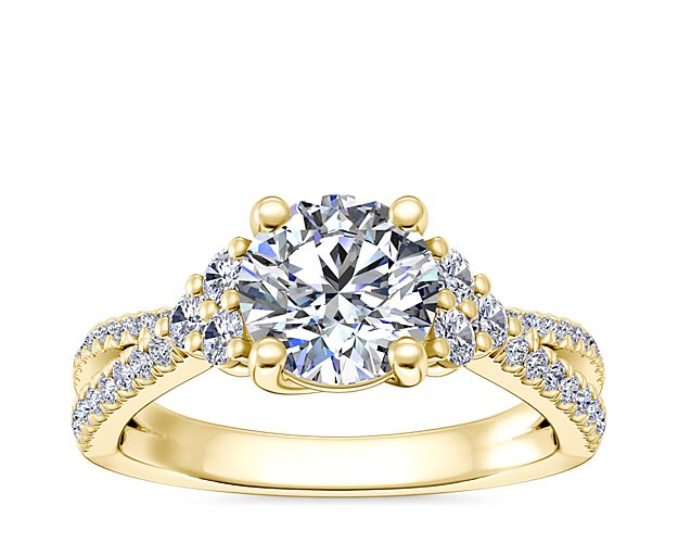 Express undying love with this elegant engagement ring featuring a gracefully criss-crossing design crafted from lustrous 14k yellow gold. The stunning center stone is accentuated by three accent diamonds on either side, and a trail of pavé-set diamonds shimmering down the shank.