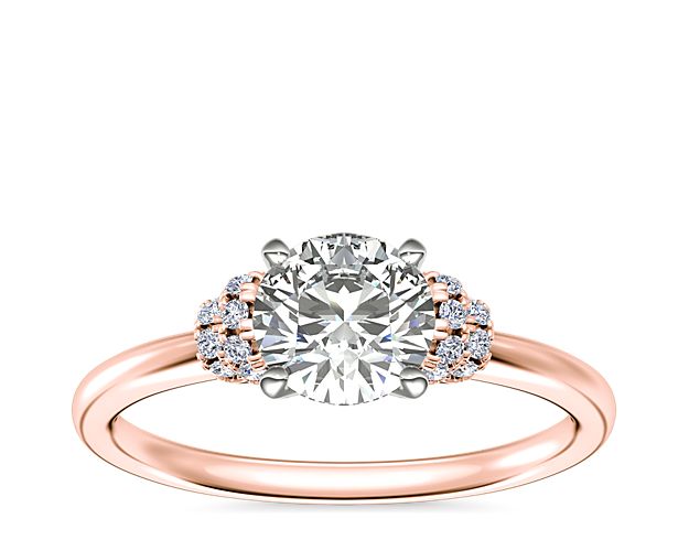 This elegant engagement ring promises plenty of sparkle, with intricate pavé-set diamonds shimmering on the sides of the center stone setting. It is crafted from 14k rose gold that promises a beautifully warm luster.