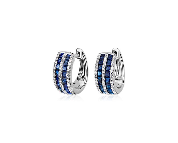 Set in 14k white gold, these huggie hoop earrings feature two layers of princess cut sapphires surrounded on all sides by a band of diamonds.
