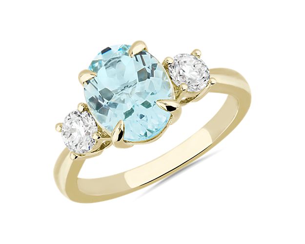 This elegant statement ring features a gorgeous oval-cut aquamarine nestle at its centre, with two accent stones adding sparkle. Warmly lustrous 14k yellow gold design promises a look of classic luxury and quality.