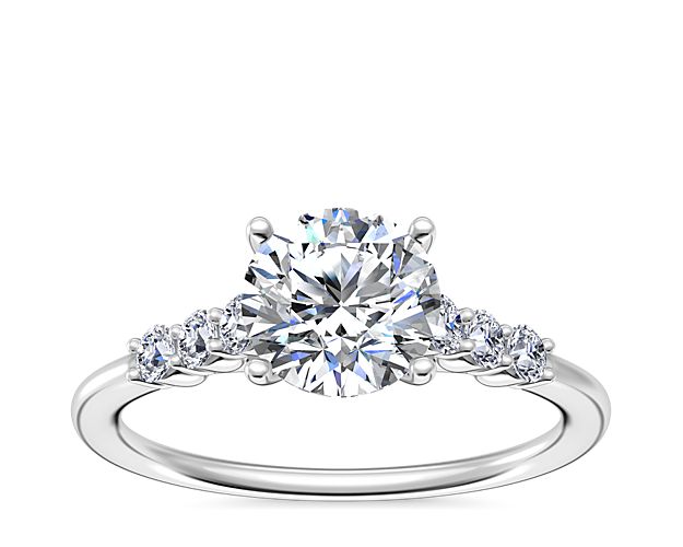 Accent diamonds in shared prong settings lend breathtaking sparkle to the shank of this cathedral engagement ring. It features beautifully lustrous platinum design for enduring luxury.