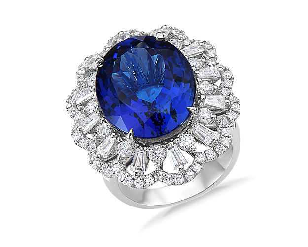 Summon attention with this stunning cocktail ring featuring a soothing blue tanzanite stone nested in a floral halo of round and baguette diamonds. Set in bright 18k white gold, this ring is the perfect statement piece.