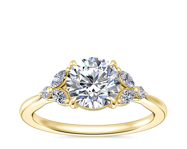 This mesmerizing engagement ring is artfully crafted from warmly lustrous 14k yellow gold. It features marquise-cut diamonds surrounding the center stone, creating a romantic floral-inspired effect.