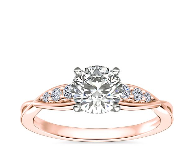 Gracefully twisting detail and sparkling accent diamonds add elegant beauty to the shank of this traditional engagement ring. The 14k rose gold design promises a look inspired by vintage romance.
