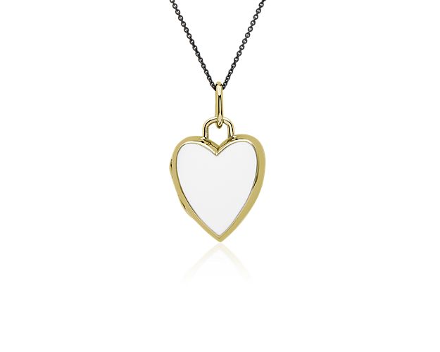 This heart-shaped locket is crafted sterling silver and coated in an 18k yellow gold vermeil. It features white enamel that is beautifully complemented by the warmth of the gold.