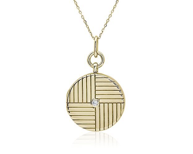 Timelessly luxurious, this 18k yellow gold round locket features engraved lines with a diamond set in the center. It opens to hold a photo and comes complete with an 18k yellow gold chain.