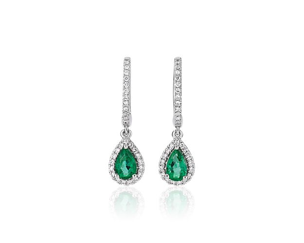 Crafted from luxurious white gold, these drop earrings feature graceful design with brilliant green pear-cut emeralds adding rich color. Accent diamonds form a brilliant halo around each emerald and add sparkle.