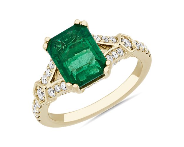 A gorgeously green emerald summons the eye to this ring crafted from beautifully lustrous 14k yellow gold. The split shank design is gorgeously accented by shimmering diamonds that elevate this ring with dramatic sparkle.