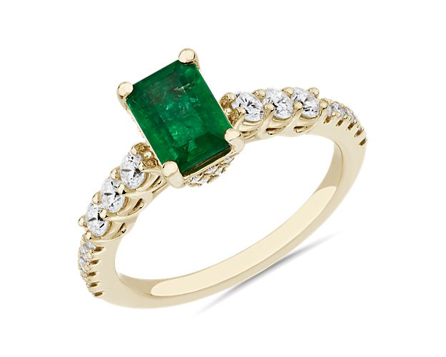 The verdant hue of the emerald-cut centre emerald beautifully pairs with the gleaming 14k yellow gold design of this ring. To either side of the centre stone, accent diamonds lend dramatic sparkle.