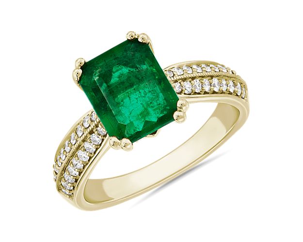 Summon their eye with this statement ring boasting a brilliantly hued emerald-cut emerald framed by dual rows of accent diamonds running along the split shank. The warm gleam of the 14k yellow gold looks lovely next to the cool green of the emerald.