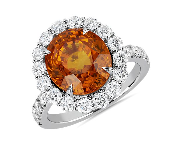 Taking center stage in this ring is a brilliant orange sapphire surrounded by a halo of brightly sparkling diamonds.  This amazing piece is crafted in 18k white gold and features diamonds along the band.  This ring is accompanied by gemstone report #:CDC22081157.