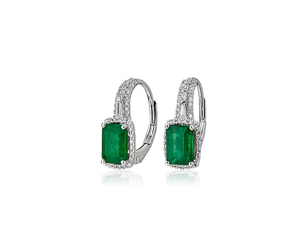 Two emeralds sparkle with bold, light-catching color. These earrings are enlivened with a brilliant halo of round diamonds set in 14k white gold.