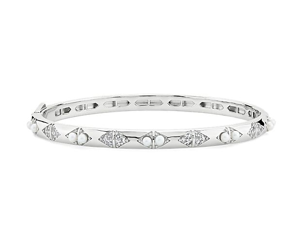 This sterling silver bangle bracelet showcases lustrous Freshwater pearls and sparkling white topaz.