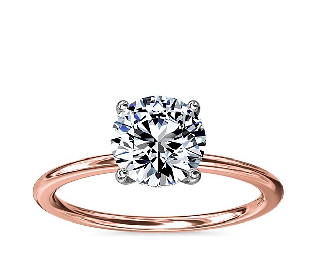 A reflection of love made to last a lifetime, this thin-shank 14k rose gold engagement ring is flawlessly designed with a platinum ring head uplifting a single center stone and a hidden halo of diamonds nestled underneath.