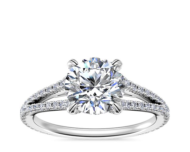 Every love story has a beginning. Write yours with an 18k white gold engagement ring designed with an elegant split shank accentuated by strings of demure diamonds set into the band reflecting brilliant light around its center stone.