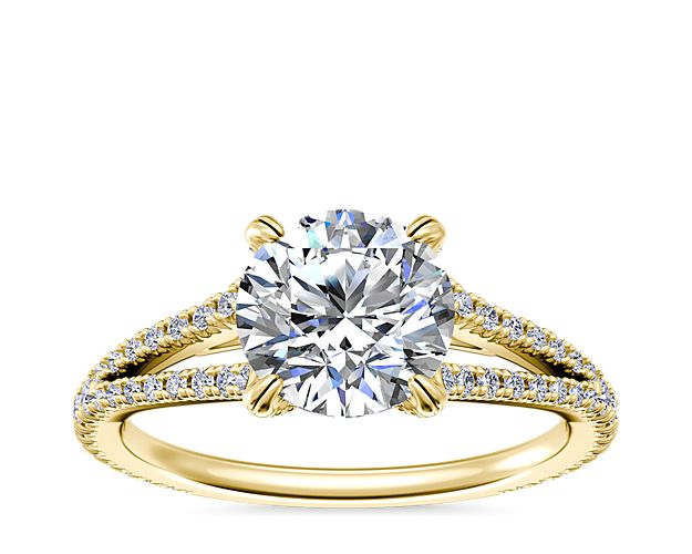 Every love story has a beginning. Write yours with an 18k yellow gold engagement ring designed with an elegant split shank accentuated by strings of demure diamonds set into the band reflecting brilliant light around its center stone.