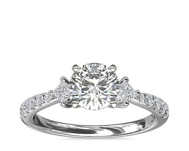 Go for a touch of whimsy with a beautiful design set in 14k white gold. This stunning style features two east-west princess-cut diamond sidestones and 10 round pavé-set diamonds flanking the center stone of your choice.
