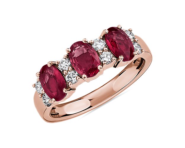 Elegant in design, this ring features three vivid rubies accented with rows of brilliant diamonds set in 14k rose gold.