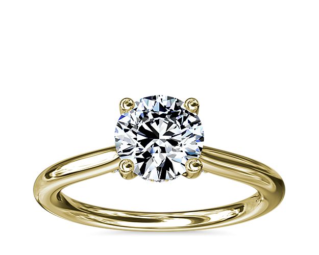 Classic from a bird's-eye view, this 14k yellow gold solitaire has a delicate diamond profile and slight cathedral that put your center stone on display.