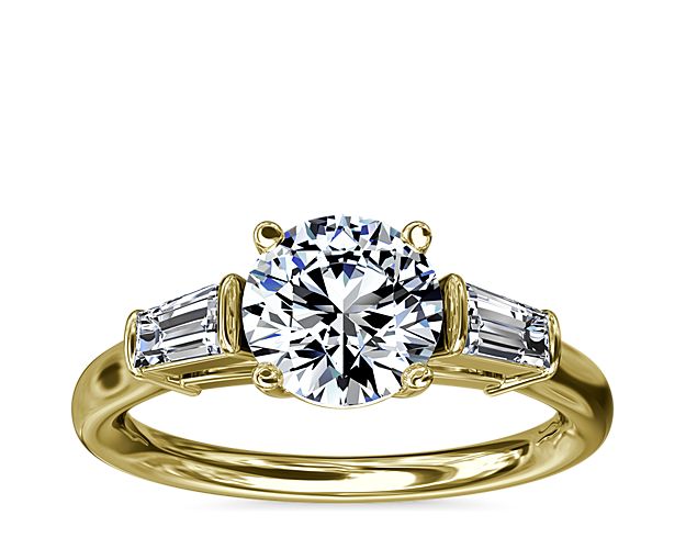 A timeless symbol of love and beauty, this 18k yellow engagement ring marries Art Deco-inspired style with pure elegance as twin tapered baguette diamonds frame a center stone casting their everlasting light in every direction.