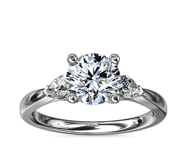An opulent 18k white gold setting embraces your precious diamond while pear-shaped side stones add a fancy-cut edge.