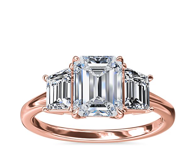 An enduring symbol of love, this 18k rose gold engagement ring showcases two trapezoid-shaped side stones framing your brilliant center stone creating a beautiful balance of symmetry and timeless style.