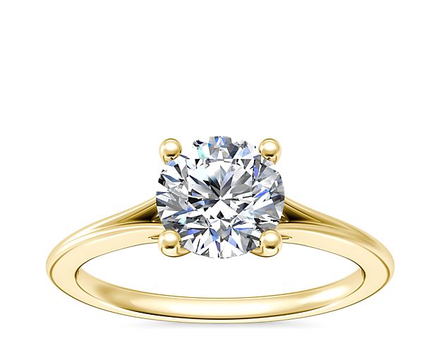 Petite hollows on either side of a dazzling center diamond add depth to this classic solitaire setting crafted with 14k yellow gold.