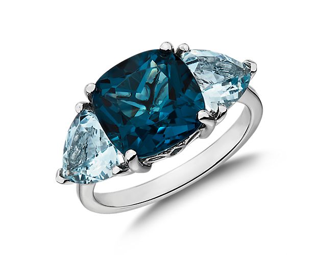Evoking the untamed beauty of the sea, two trillion-cut light blue aquamarines surround a swelling center cushion-cut aquamarine giving this white gold ring attention-grabbing appeal.