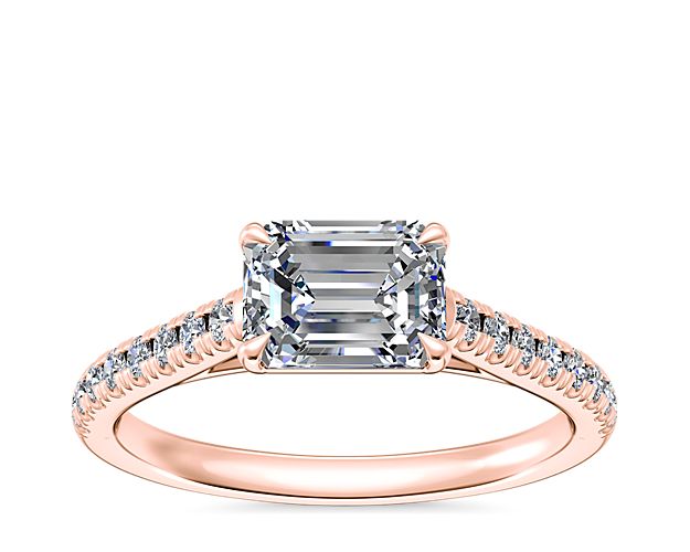 Celebrate your love with a truly stunning engagement ring like this 14k rose gold piece that features an east-west facing center stone surrounded by a line of smaller diamonds. This setting supports your choice of emerald, pear, marquise, or oval-cut diamond.