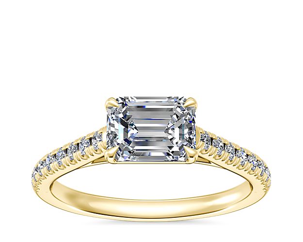 14k yellow gold warms the profile of this engagement ring featuring a row of diamonds on either side of an east-west facing center stone. This setting supports your choice of emerald, pear, marquise, or oval-cut diamond.