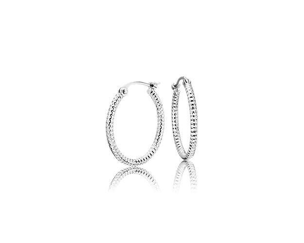 These small platinum hoop earrings have a subtly patterned, shimmer-cut surface that catches the light for just a glint of shine at the ear. The petite hoop size makes these earrings an everyday staple.