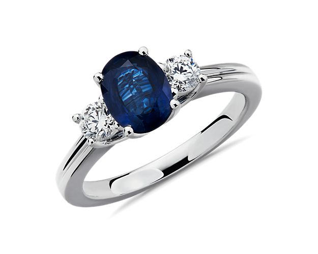 Graceful in design, this sapphire and diamond ring features a deep-blue oval sapphire set in 18k white gold and perfectly accented by two round brilliant diamonds for a stunning three-stone ring.