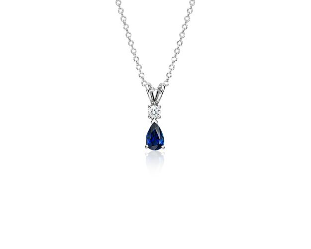 Our 18k white gold pendant holds a single round diamond that sits above an elegant pear shaped sapphire. This pendant is suspended from an 18k white gold cable-link chain.