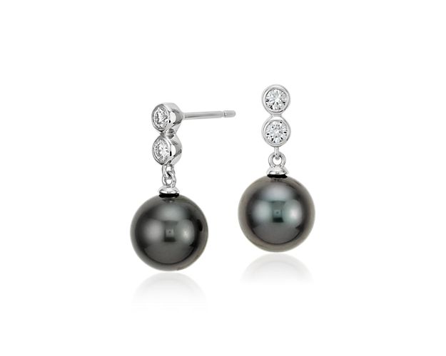 Lustrous Tahitian pearls are suspended by two bezel set diamonds in these drop earrings.