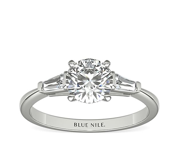 This iconic ring features two tapered baguette-cut diamonds set in classic bar channels, brilliantly framing the center diamond of your choice. Crafted in high polish platinum, this ring offers a petite silhouette with timeless style.