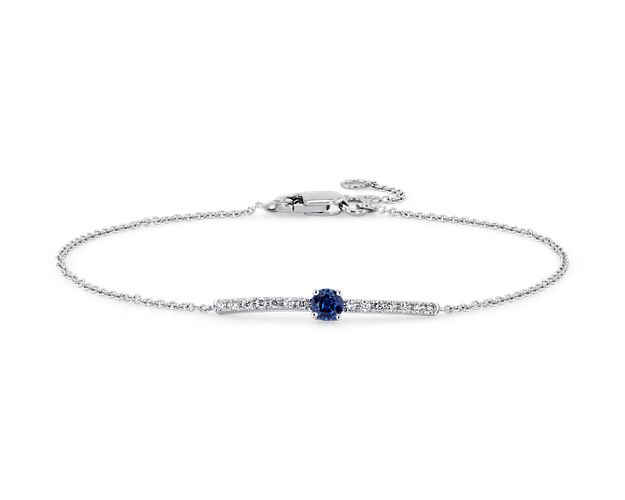 A velvety sapphire adds a pop of color to the bar of brilliant diamonds featured on this 14k white gold bracelet.