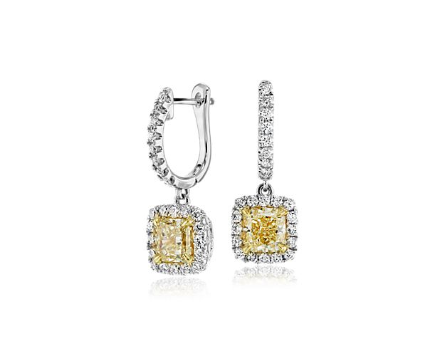 Enliven your earlobes with a pair of sunny, radiant-cut center diamonds surrounded by a halo of brilliant round diamonds. 18k white gold accented with 18k yellow gold finishes this light-catching look.