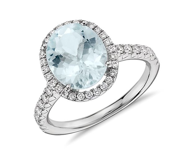 A vision of coastal color, this aquamarine and diamond halo ring features a light blue oval aquamarine gemstone framed by a halo of pavé set round brilliant diamonds set in polished 18k white gold.