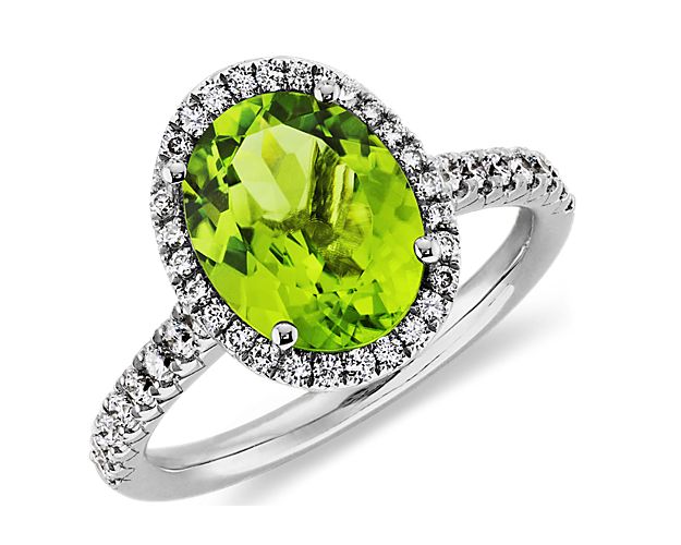 A vision of vivid color, this peridot and diamond halo ring features a vibrant green oval peridot gemstone framed by a halo of pavé set round brilliant diamonds set in polished 18k white gold.