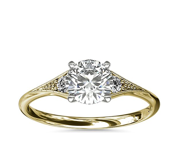 Vintage-inspired, this delicate 14k yellow gold engagement ring features 2 pavé-set round diamonds surrounded by a milgrain edge.