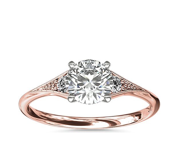 Vintage-inspired, this delicate 14k rose gold engagement ring features 2 pavé-set round diamonds surrounded by a milgrain edge.