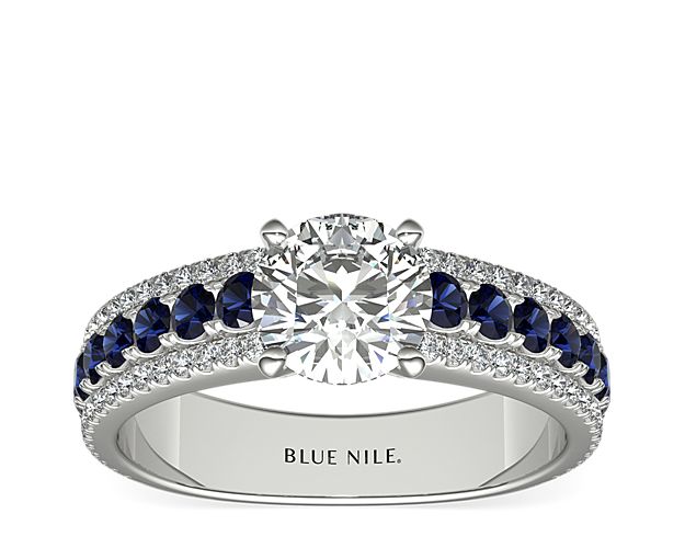 A row of boldly hued sapphires, flanked by dazzling pavé diamonds, provide a dazzling complement to the brilliant center stone of your choice in this gorgeous 14k white gold engagement ring.
