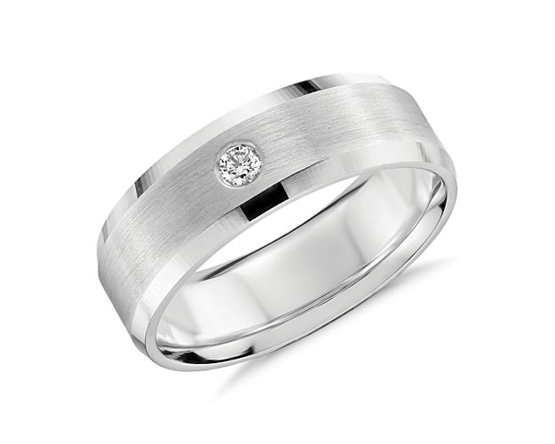 Modern in design, this subtle wedding band encompasses a single diamond, burnished-set in the center of the ring.