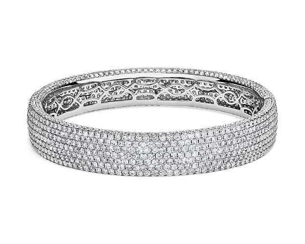 Row after twinkling row of round-cut diamonds pave this sparkling bangle bracelet, bringing breath-taking brilliance to any ensemble. 18k white gold peeks out between settings for a subtle touch of extra elegance.