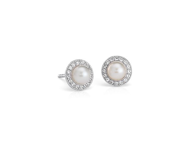 These petite Freshwater cultured pearl stud earrings are crafted in elegant sterling silver. Two round white pearls are encircled by the subtle glimmer of white topaz gemstone halos and a milgrain edge that adds vintage-inspired detail. Their dainty size makes them great for everyday wear, or an understated bridal accent.